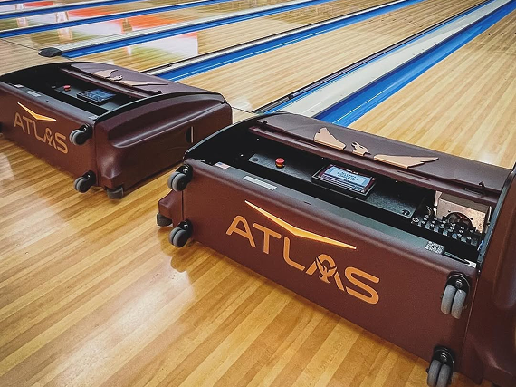 Two Kegel Atlas lane machines in maroon with gold branding, positioned on wooden bowling lanes